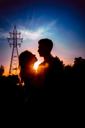 Silhouettes of a guy and girl in a field on a sunset background.の写真素材