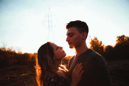 Silhouettes of a guy and girl in a field on a sunset background.の写真素材