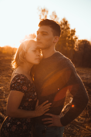 guy and girl in the field on the sunset background.の写真素材