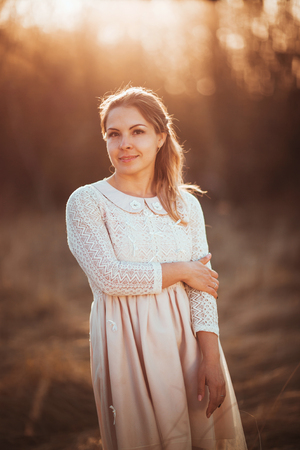 Beautiful girl standing in a field on a sunset background.の写真素材