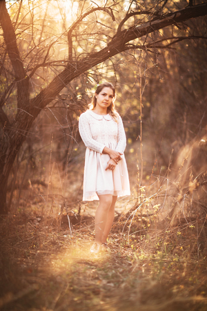 Beautiful girl standing in a field on a sunset background.の写真素材