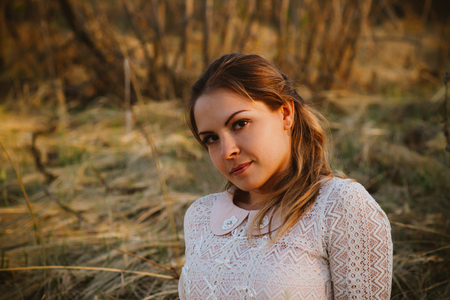 girl is sitting in the field on the sunset background.の写真素材