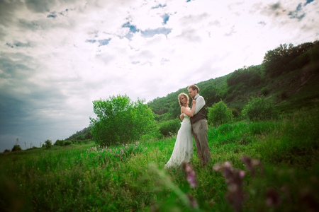 bride and groom stand on the background of the mountain and grass.の写真素材