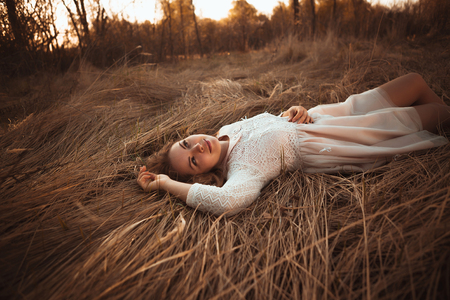 girl lying on the field on a sunset background.の写真素材