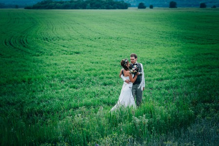 bride and groom stand on the background of the field.の写真素材