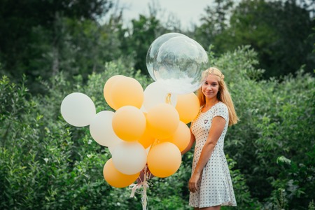 young girl with balloons on nature background.