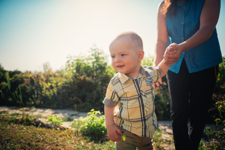 happy mother and toddler son on nature background.の写真素材