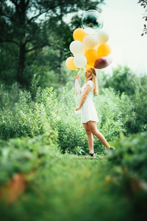 young girl with balloons on nature background.の写真素材