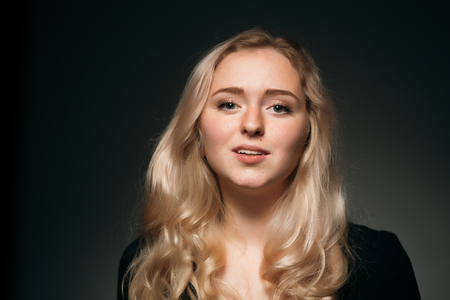 young girl blonde on a dark background.の写真素材