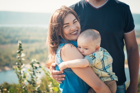 Happy family with baby son on nature background.の写真素材