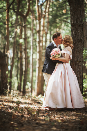 bride and groom kiss on the background of trees and forest.の写真素材