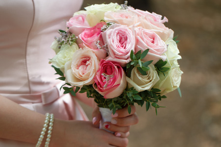 beautiful wedding bouquet of cream roses in hands of the bride.の写真素材