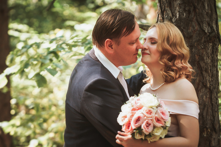 bride and groom kiss on the background of trees and forest.の写真素材