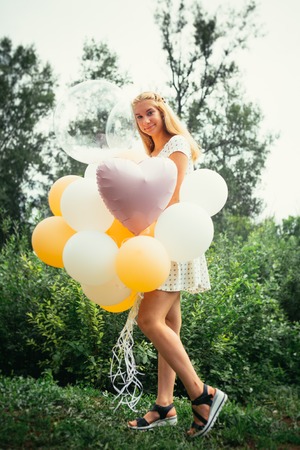young girl with balloons on nature background.の写真素材