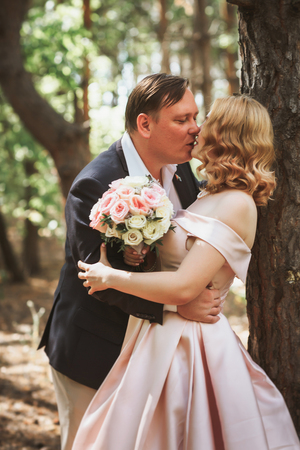 bride and groom kiss on the background of trees and forest.の写真素材