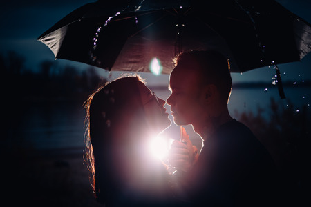 young man and woman under an umbrella and rain.の写真素材