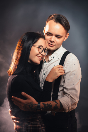 Couple in fashionable clothes on a dark smoky background.の写真素材