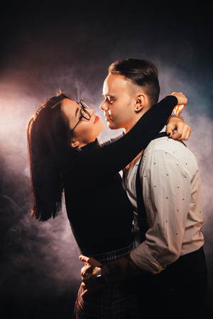 Couple in fashionable clothes on a dark smoky background.の写真素材
