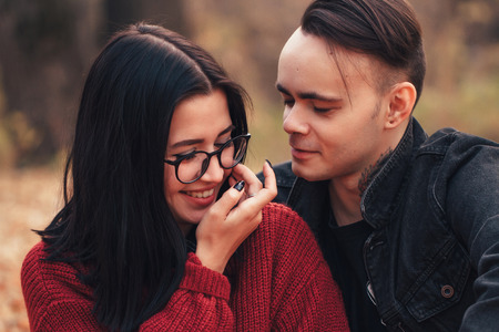 young man and young woman are sitting on a plaid in an autumn forest.の写真素材