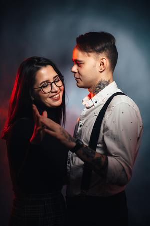 Couple in fashionable clothes on a dark smoky background.の写真素材