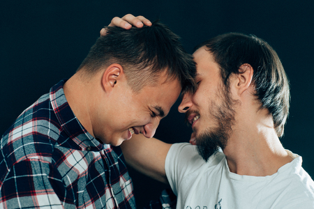 two guys hugging on a dark background.の写真素材