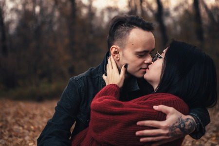 young man and young woman are sitting on a plaid in an autumn forest.の写真素材