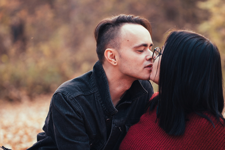 young man and young woman are sitting on a plaid in an autumn forest.の写真素材