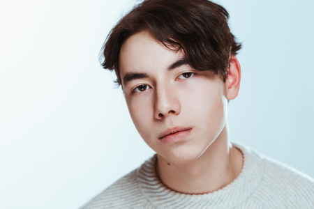 Studio portrait young man in grey sweater on white background.の写真素材