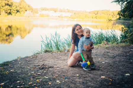 happy mother and toddler son on nature background.の写真素材