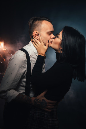 Couple in fashionable clothes on a dark background with smoke.の写真素材