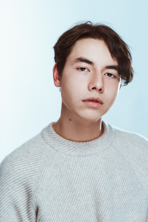 Studio portrait young man in grey sweater on white background.の写真素材