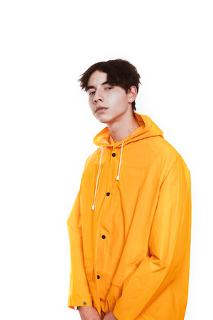 portrait of a teen guy in a yellow raincoat brunette in the studio.の写真素材