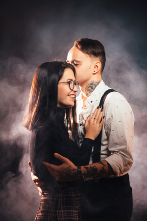 Couple in fashionable clothes on a dark smoky background.の写真素材