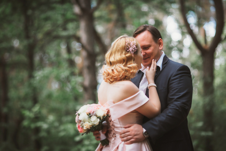 bride and groom kissing in the summer forest.の写真素材