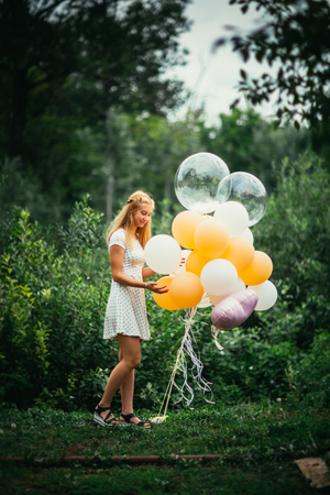 young girl with balloons on nature background.の写真素材