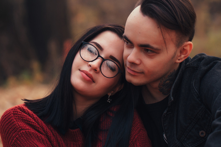 young man and young woman are sitting on a plaid in an autumn forest.の写真素材