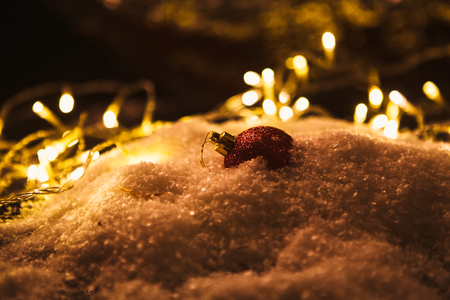 red Christmas ball and luminous garland on the snow.の写真素材