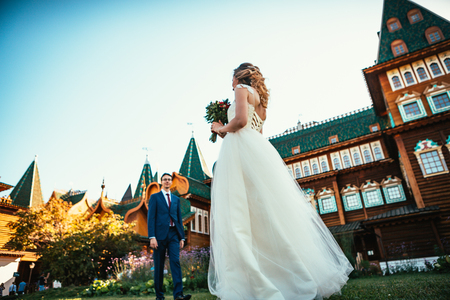 Walk young bride and groom on old house background.の写真素材