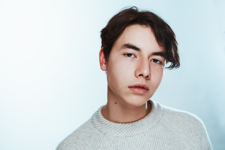 Studio portrait young man in grey sweater on white background.の写真素材