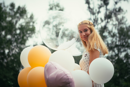 young girl with balloons on nature background.の写真素材