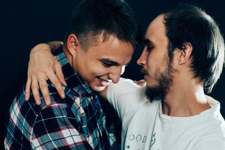 two guys hugging on a dark background.の写真素材