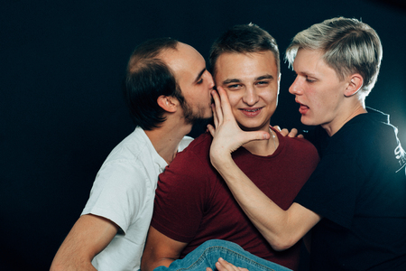three guys are gay on dark background.の写真素材