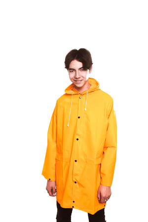 portrait of a teen guy in a yellow raincoat brunette in the studio.の写真素材
