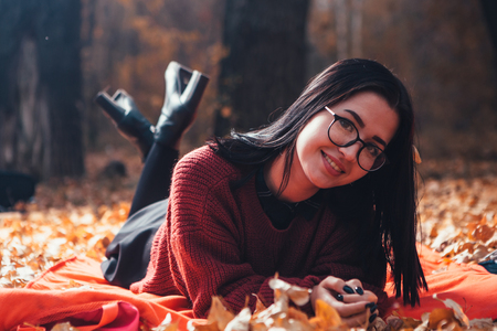 Girl lying on the plaid in autumn forest, nature background.の写真素材