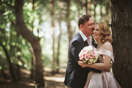 bride and groom kiss on the background of trees and forest.の写真素材