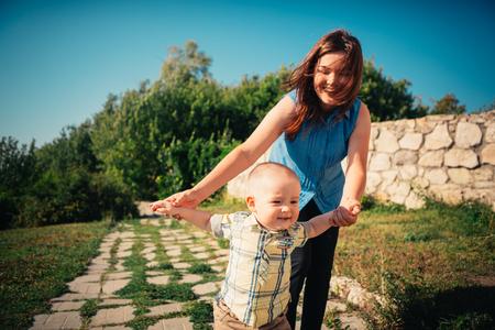 happy mother and toddler son on nature background.の写真素材
