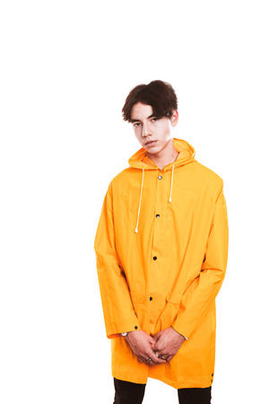 portrait of a teen guy in a yellow raincoat brunette in the studio.の写真素材