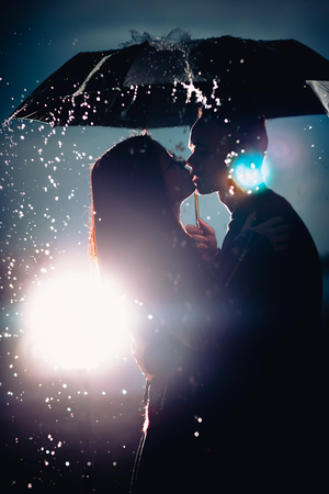 young man and woman under an umbrella and rain.の写真素材