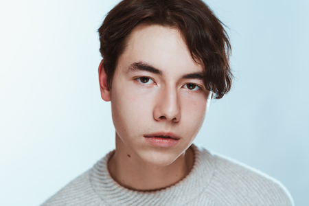 Studio portrait young man in grey sweater on white background.の写真素材