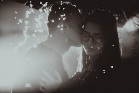 black white photo young couple standing under a dark umbrella.の写真素材